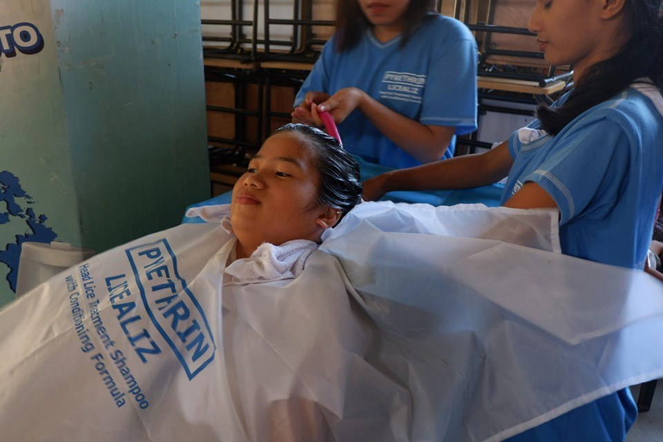 A student from Cesareo Villa Abrille Elem. School, Davao City having her hair shampooed with LiceAliz.