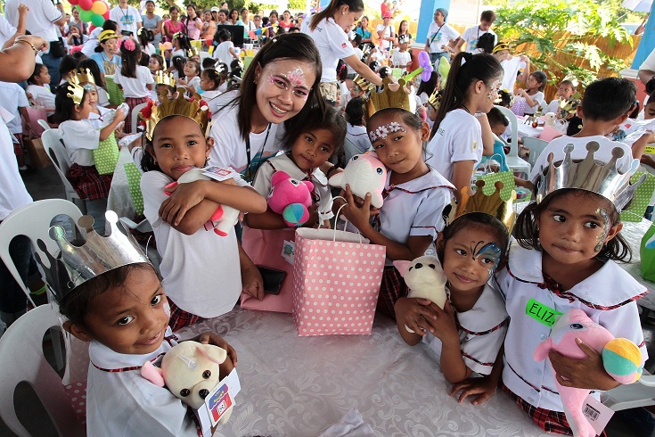 Christmas cheer fills the air as an employee volunteer of The SM Store and the children of Looc Elementary School smile for the camera after the Share a Toy activity. 